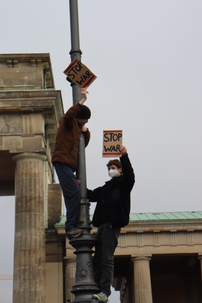 Kids climbing a street light holding anti war protest signs in Berlin, Germany