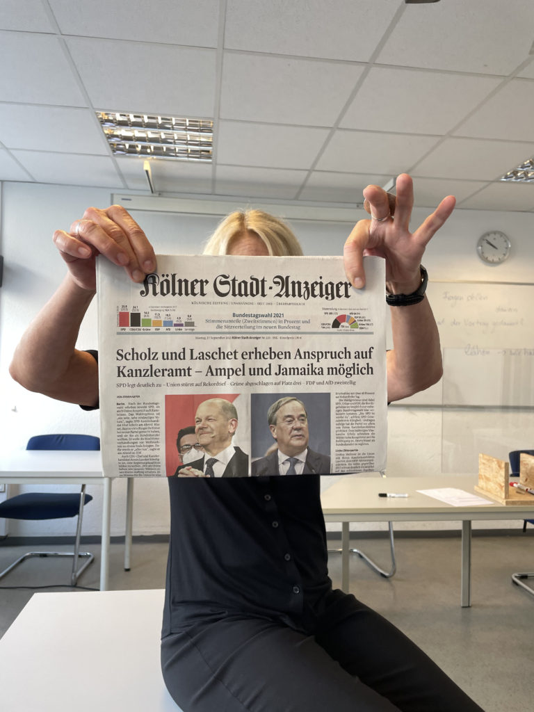 language school teacher holding up the days newspaper